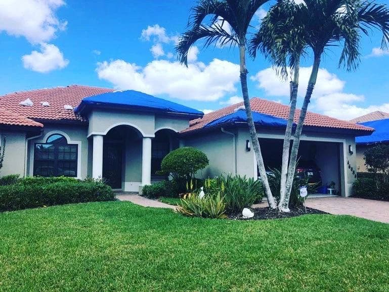 Hurricane emergency roof repair in Florida by Vreeland Roofing. Blue tarps covering a damaged tile roof, protecting the home after storm damage. Expert storm response and temporary roof protection services.